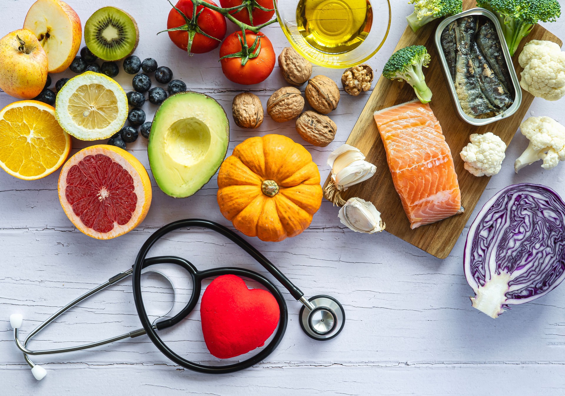 Stethoscope and a heart surrounded by healthy food: fruit, vegetables, fish. Healthy food concept to prevent diseases Stethoscope and a heart surrounded by healthy food: fruit, vegetables, fish. Healthy food concept to prevent diseases